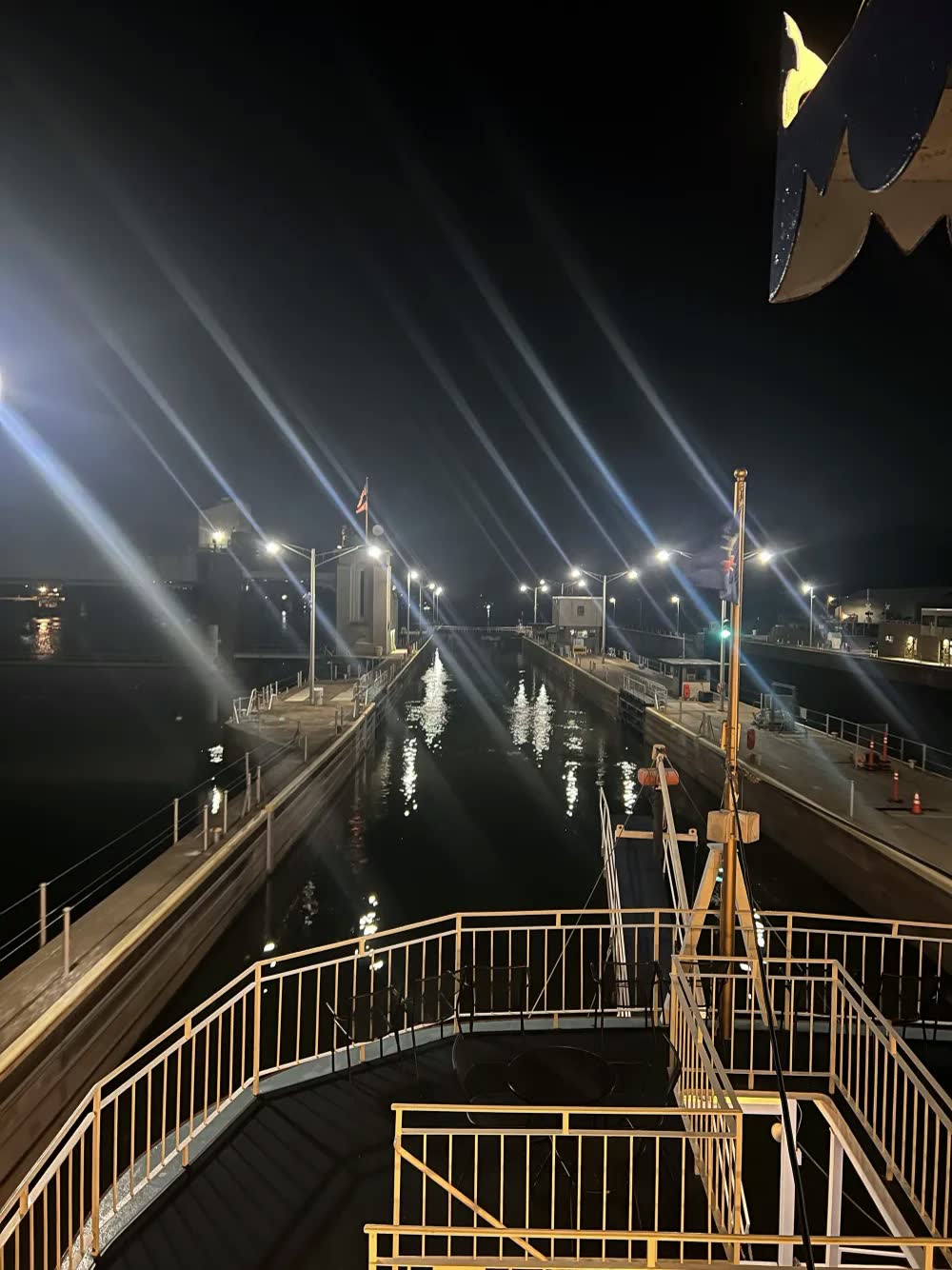 Floodlit lock walls stretching ahead of the Queen's bow at night