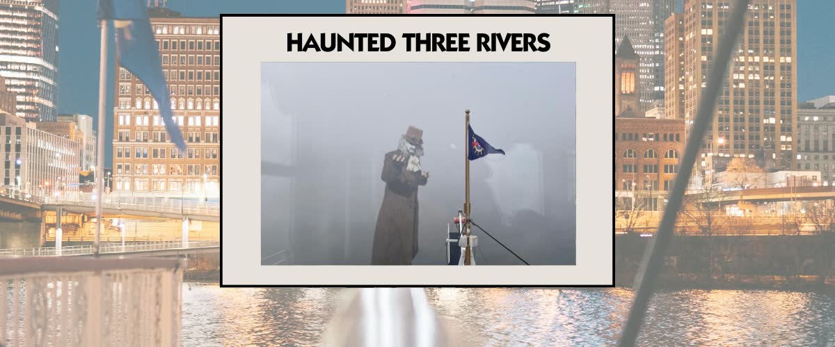 A costumed figure in a long coat and top hat on the bow of a riverboat in thick fog beside a Gateway Clipper flag
