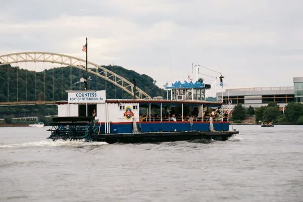 The Countess riverboat on the river with a yellow arch bridge behind it