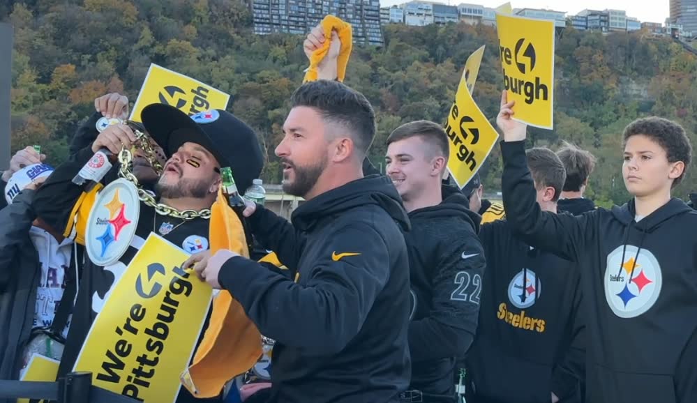 Steelers fans waving Terrible Towels and We're Pittsburgh signs at the WTAE tailgate on the riverfront