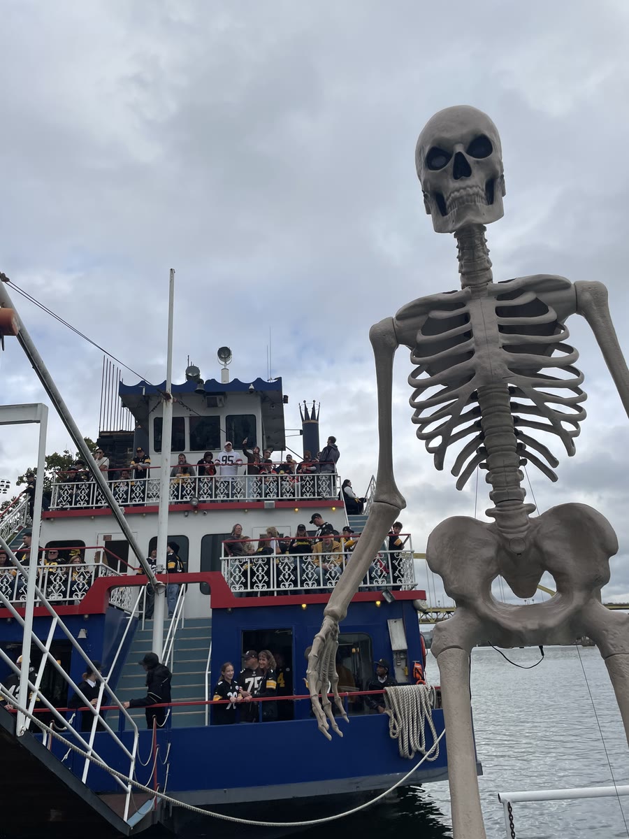 A giant skeleton decoration at the Gateway Clipper dock beside the Three Rivers Queen as guests crowd the decks