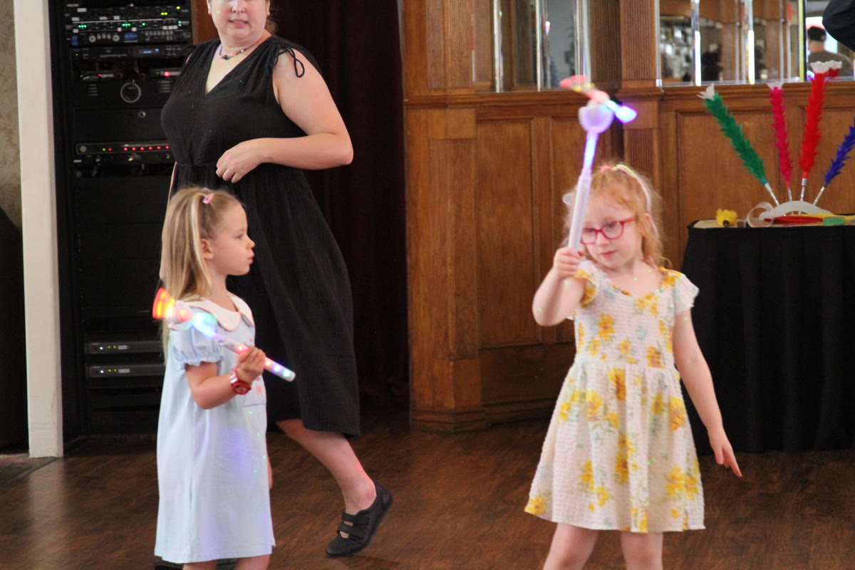 Two young girls dancing with light-up wands on the dance floor of a Gateway Clipper riverboat
