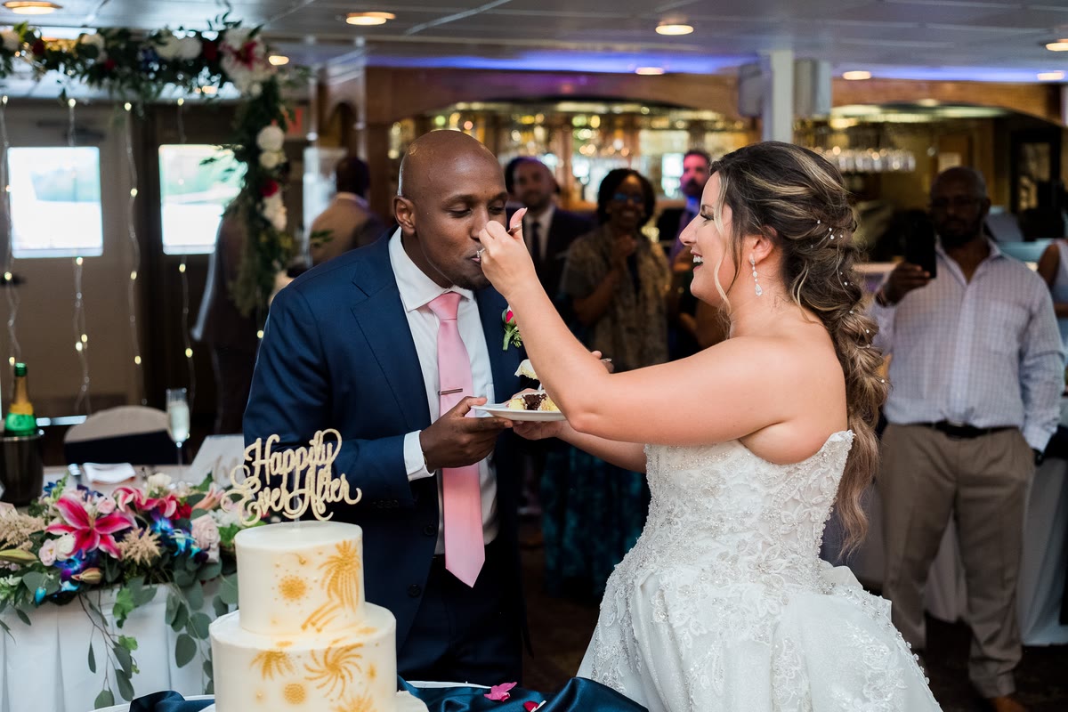 A bride and groom cut and share their wedding cake at the reception aboard a Gateway Clipper riverboat