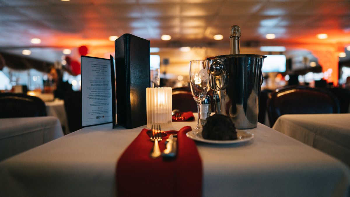 A holiday dinner table with a red runner, candle and champagne bucket