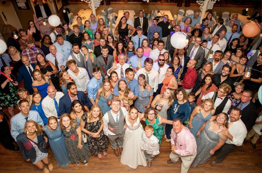 A big wedding party gathered on the dance floor, photographed from the balcony above