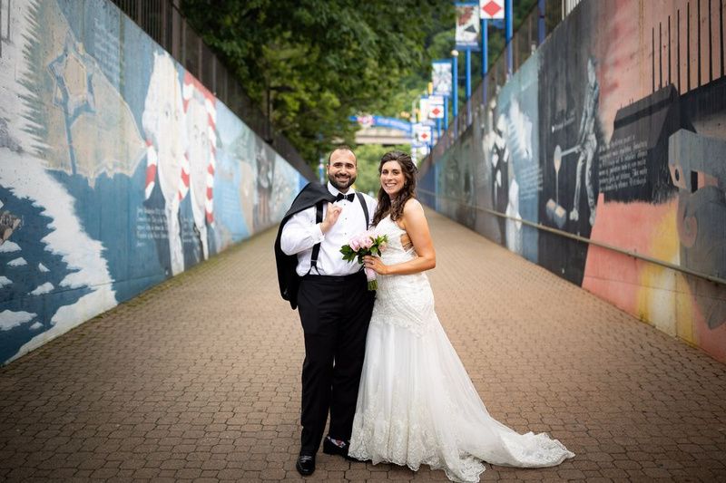 A bride and groom smiling in the mural-lined walkway to the Station Square dock