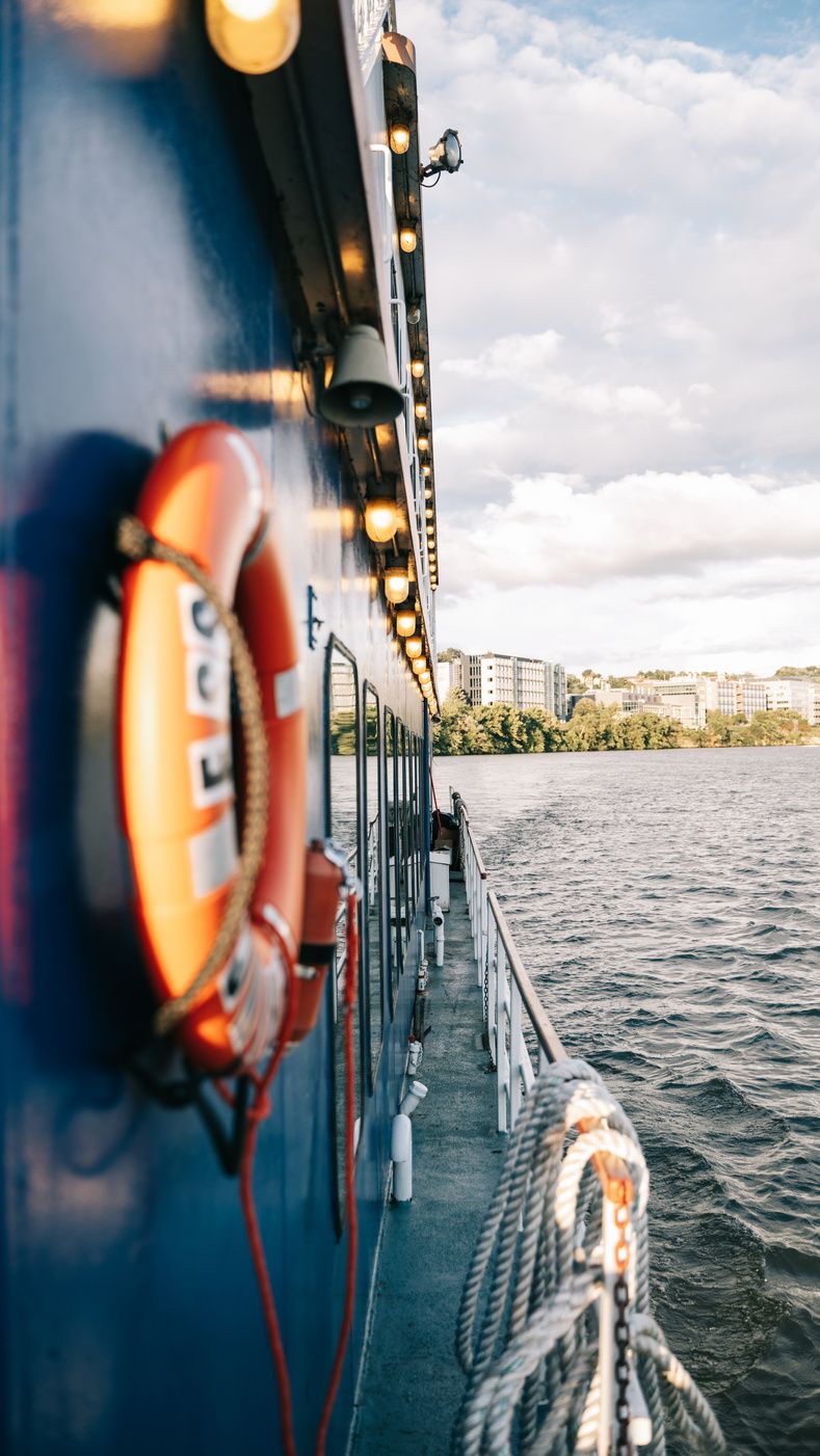 A life ring hanging on the side of a riverboat, the river rushing past below