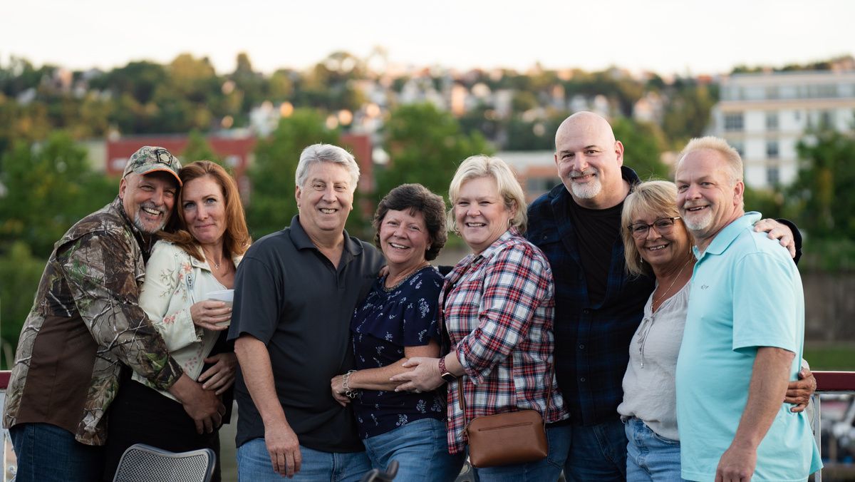 A smiling group of friends posing together at the rail on the deck of a Gateway Clipper riverboat