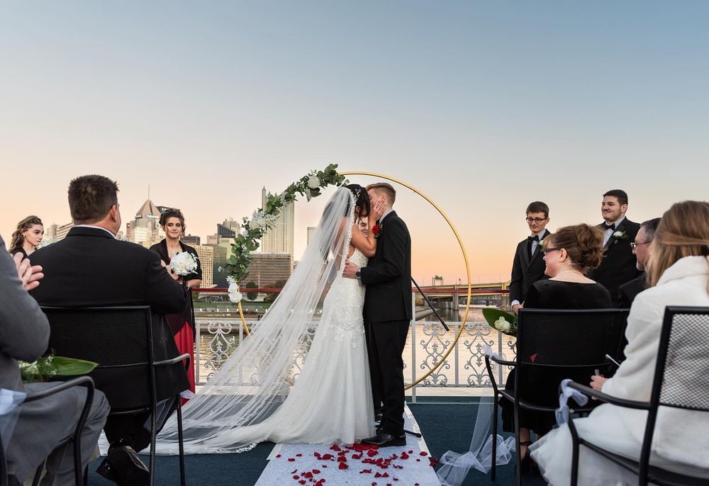 Bride and groom kissing at an outdoor wedding with guests seated around them.